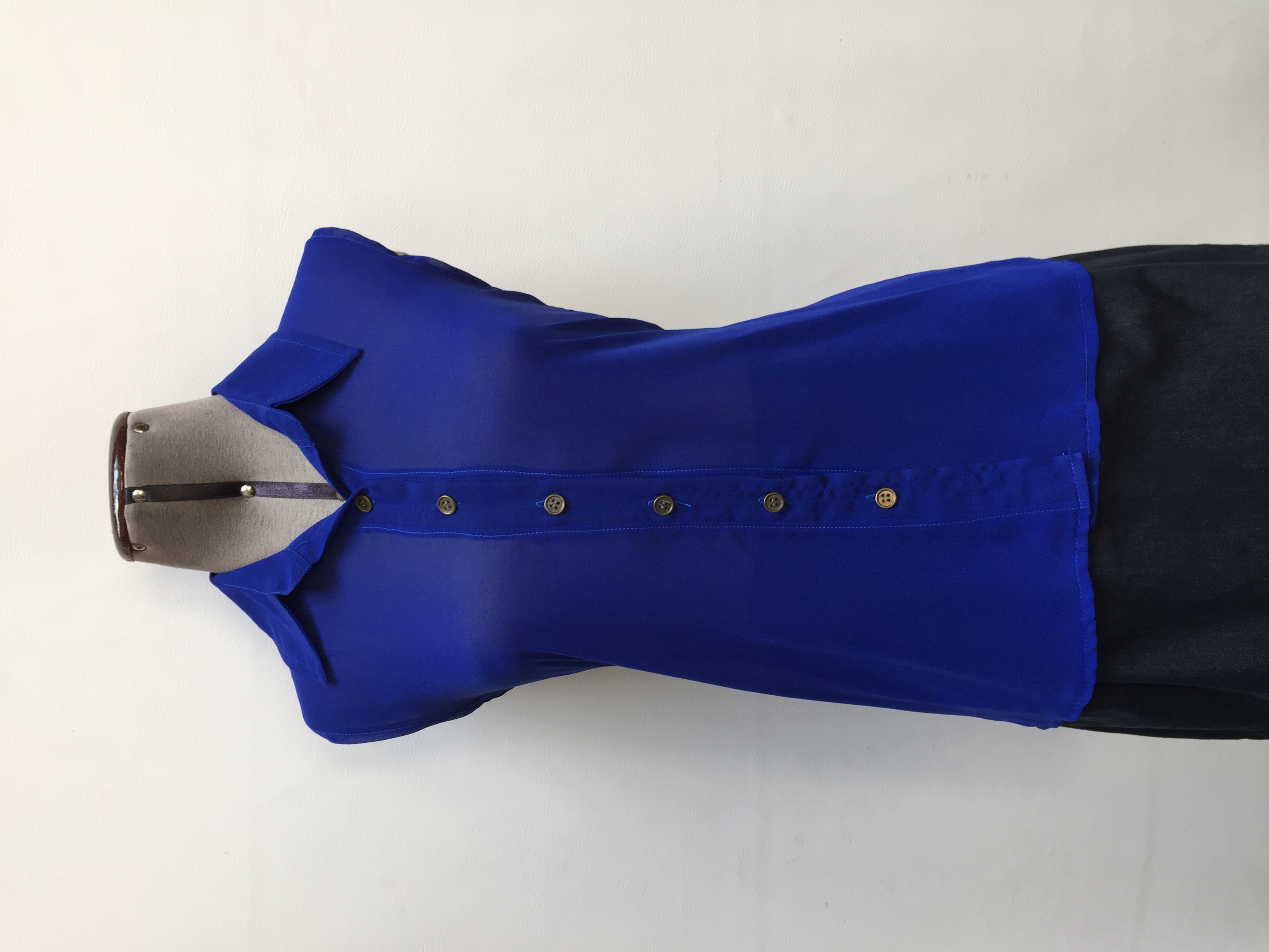 Blusa de gasa azul, cuello camisero y botones en tono bronce en el medio
Talla S (Puede ser un M chico)